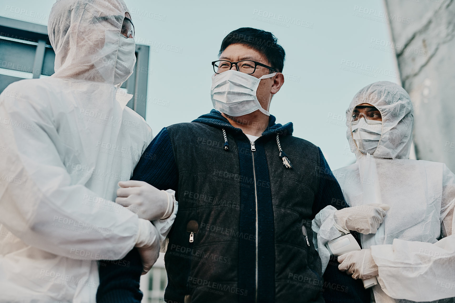 Buy stock photo Asian man breaking covid regulation getting taken away or arrested by healthcare workers wearing hazmat protective suits. Male removed for not following the rules or restrictions of the pandemic.
