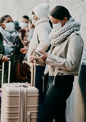 Buy stock photo Shot of a young woman using a smartphone and wearing a mask while travelling in a foreign city