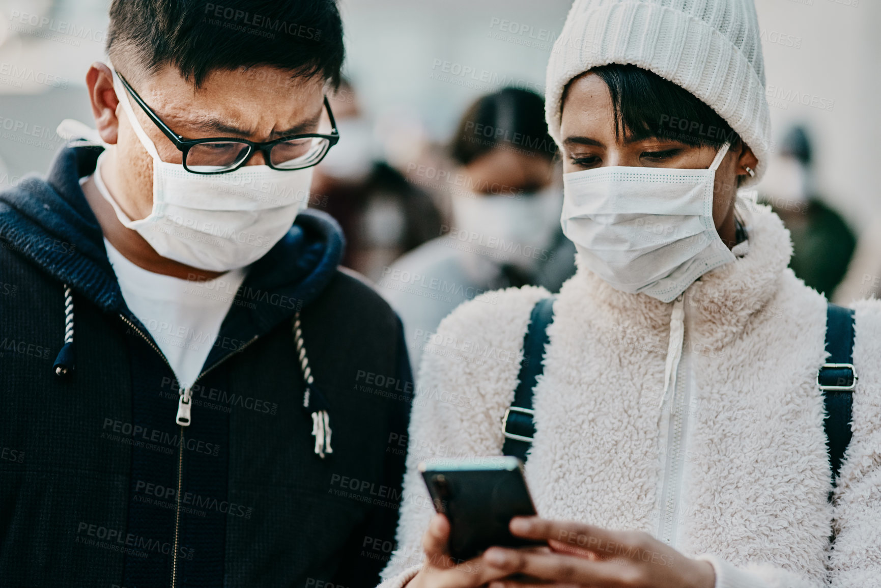 Buy stock photo Shot of a young man and woman using a smartphone and wearing masks while travelling in a foreign city