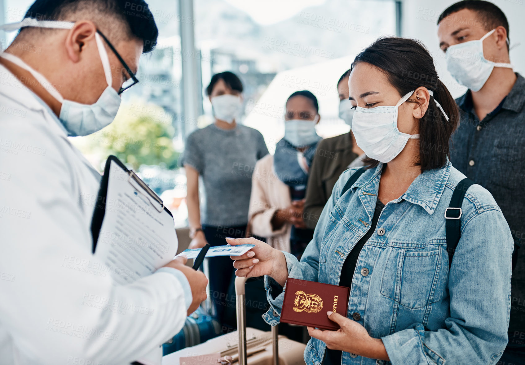 Buy stock photo Shot of a woman wearing a mask and giving her passport to a doctor in an airport