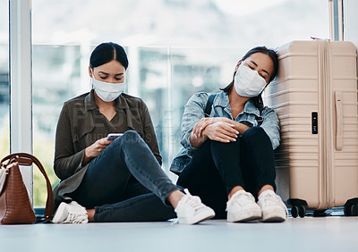 Buy stock photo Young women in quarantine after travel, wearing safety mask  to protect from covid and sitting in an airport traveling together during pandemic. Tired female friends leaving for getaway vacation