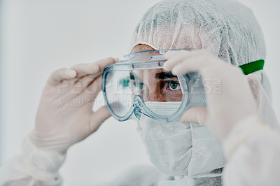 Buy stock photo Covid, pandemic of young man putting on his protective gear for health and safety from the virus. Serious professional infection fighter ready to combat the spread of the disease or illness.