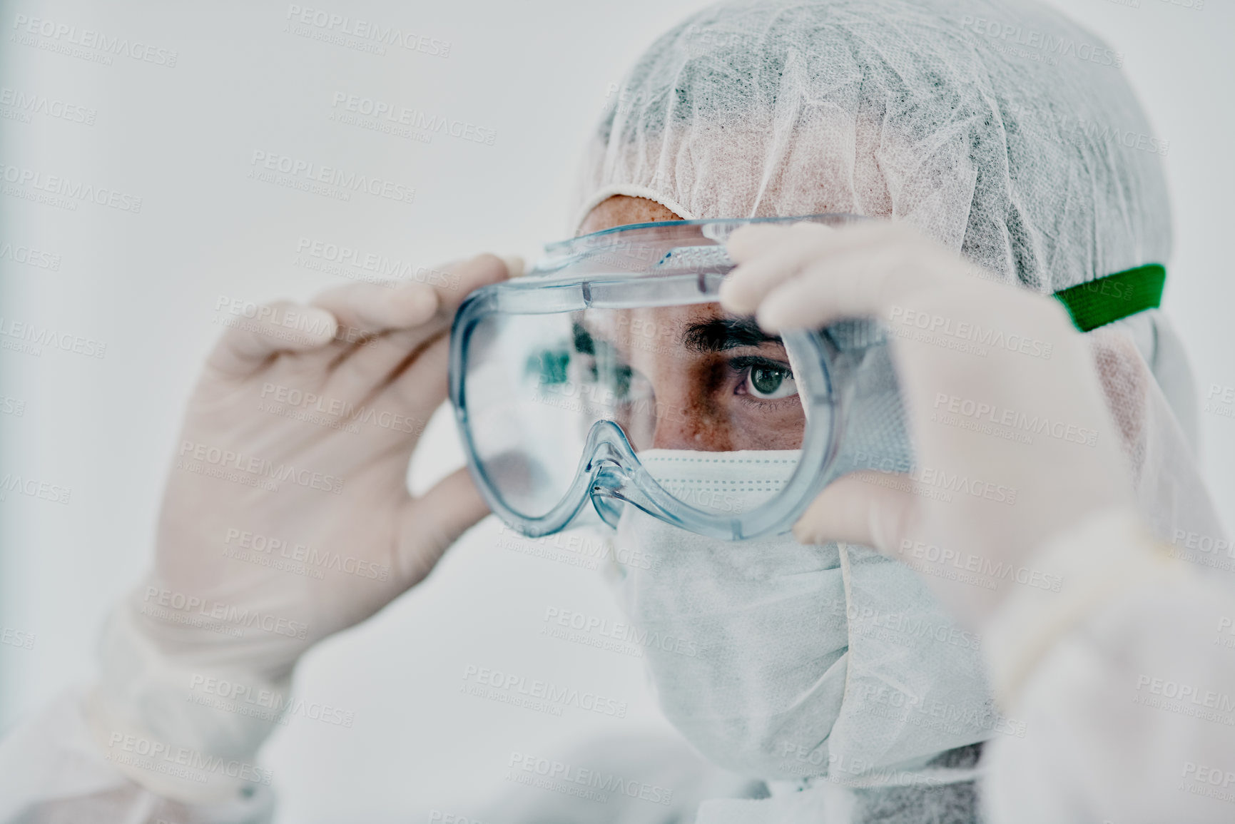 Buy stock photo Covid, pandemic of young man putting on his protective gear for health and safety from the virus. Serious professional infection fighter ready to combat the spread of the disease or illness.