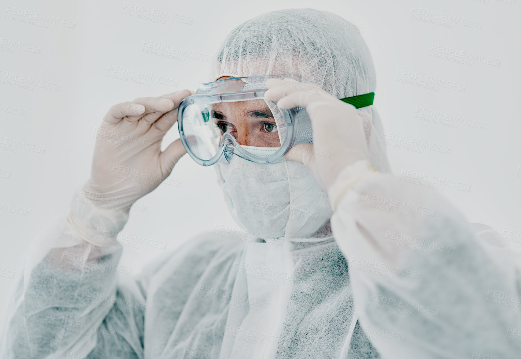 Buy stock photo Shot of a young man putting on his protective gear before the decontamination process