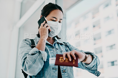 Buy stock photo Shot of a young woman wearing a mask, using a smartphone and checking the time in an airport