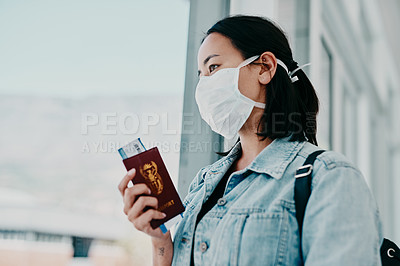 Buy stock photo Shot of a woman wearing a mask and holding her passport in an airport