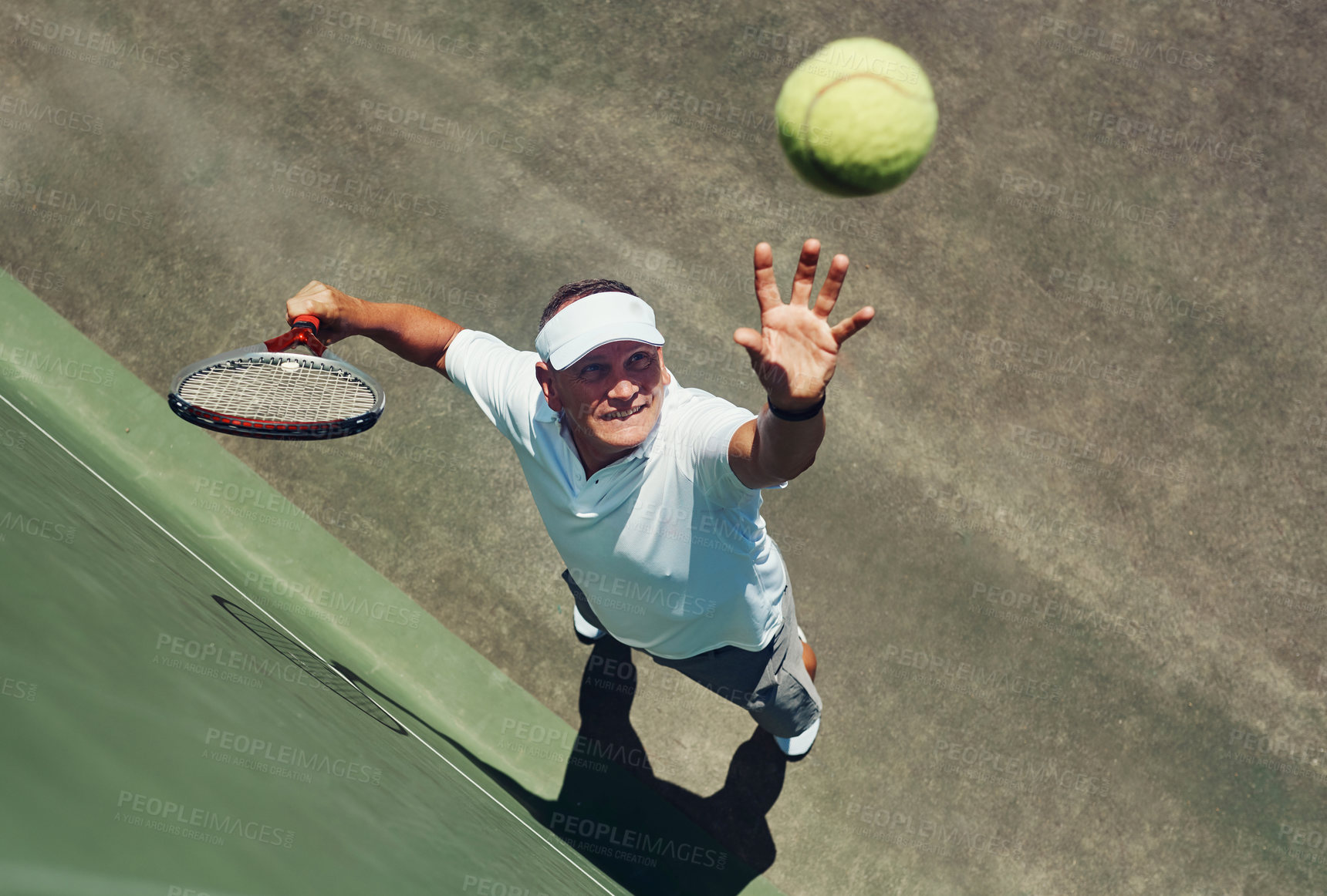 Buy stock photo High angle shot of a focused middle aged man playing tennis while about to serve the ball to his opponent outside during the day