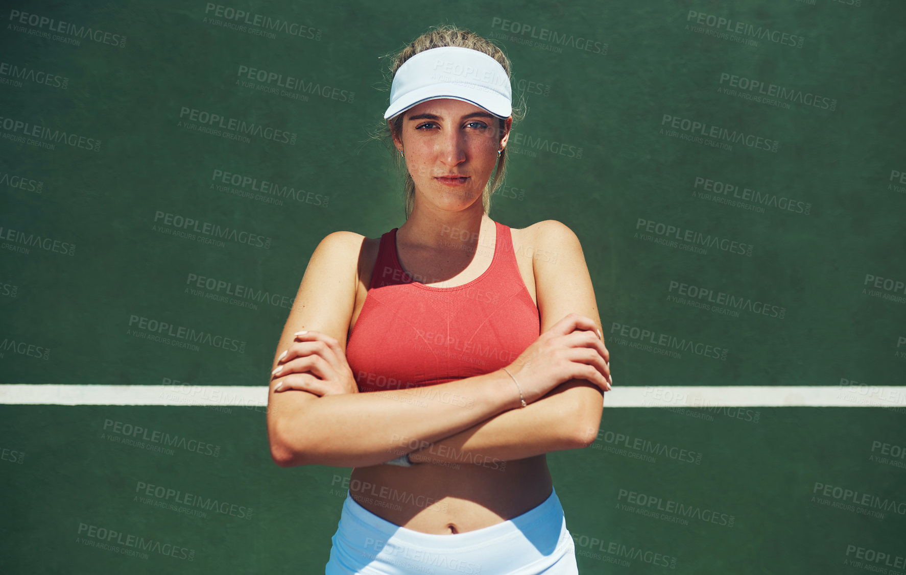 Buy stock photo Portrait of a confident young woman standing with her arms folded outside on a tennis court during the day