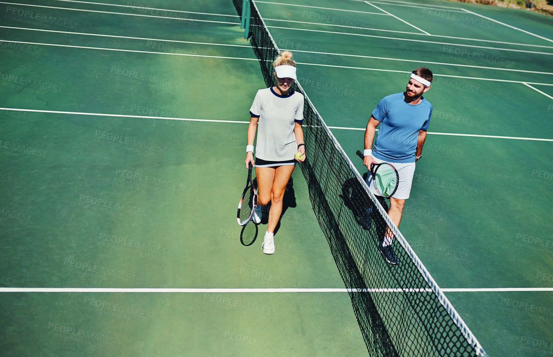 Buy stock photo Full length shot of two young tennis players talking while walking together outdoors on a tennis court
