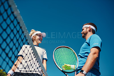 Buy stock photo Low angle shot of two young tennis players having a chat together outdoors on the court