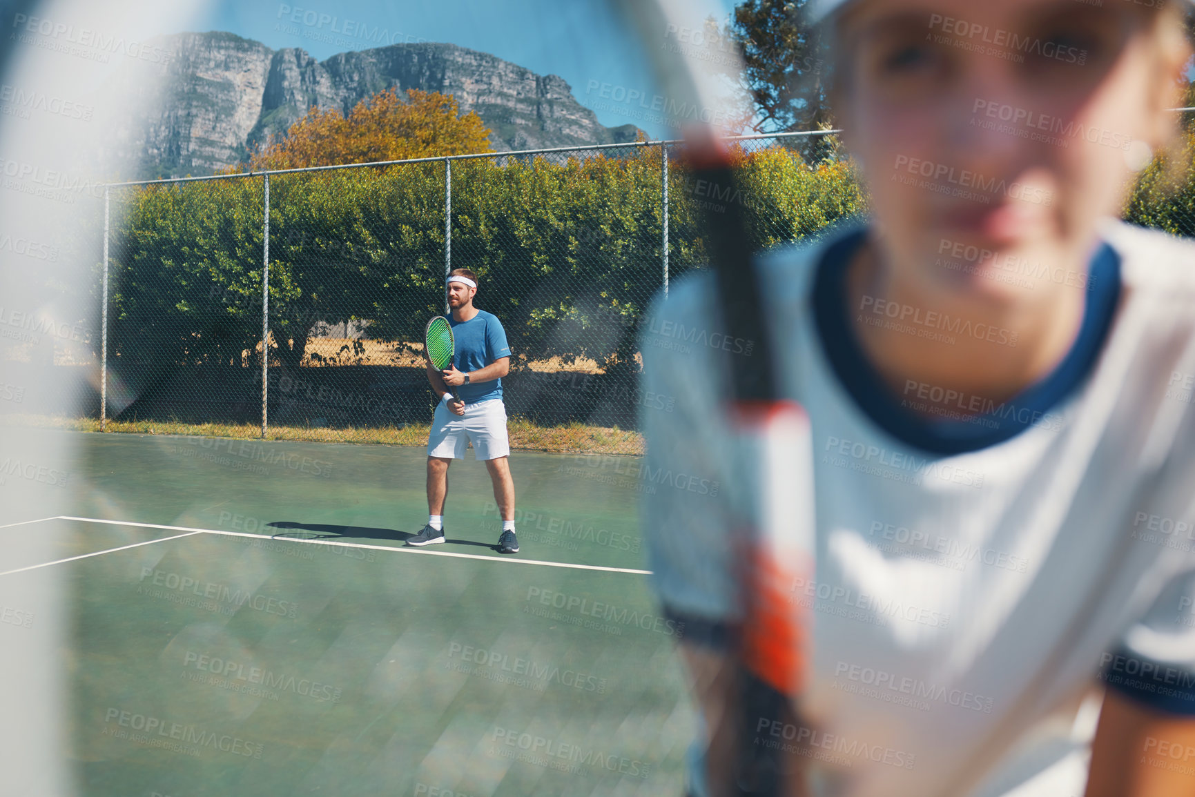 Buy stock photo Shot of a handsome young male tennis player outdoors on the court with a female teammate in the foreground