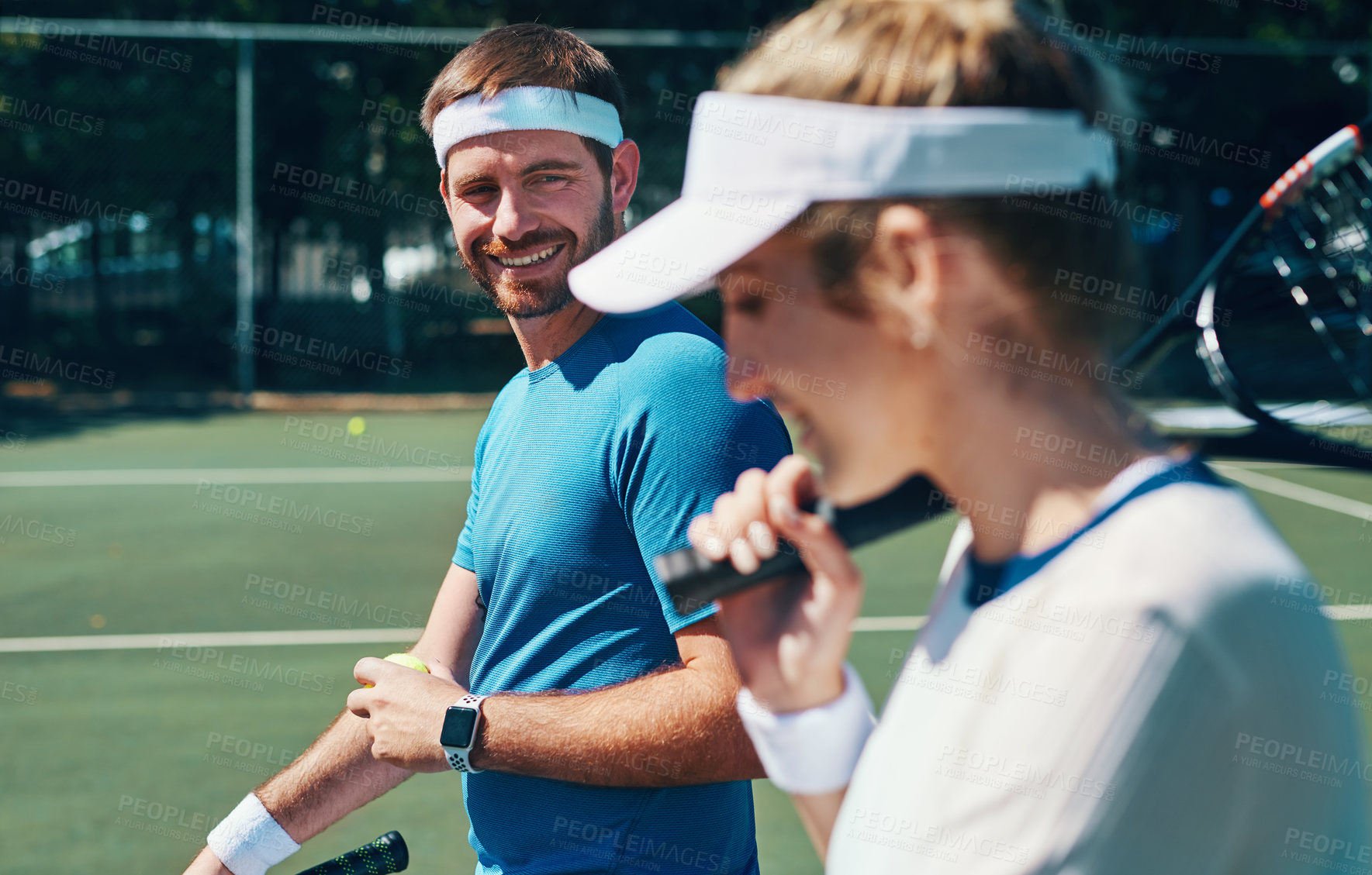 Buy stock photo Cropped shot of a handsome young male tennis player playing talking to his female teammate outdoors on the court