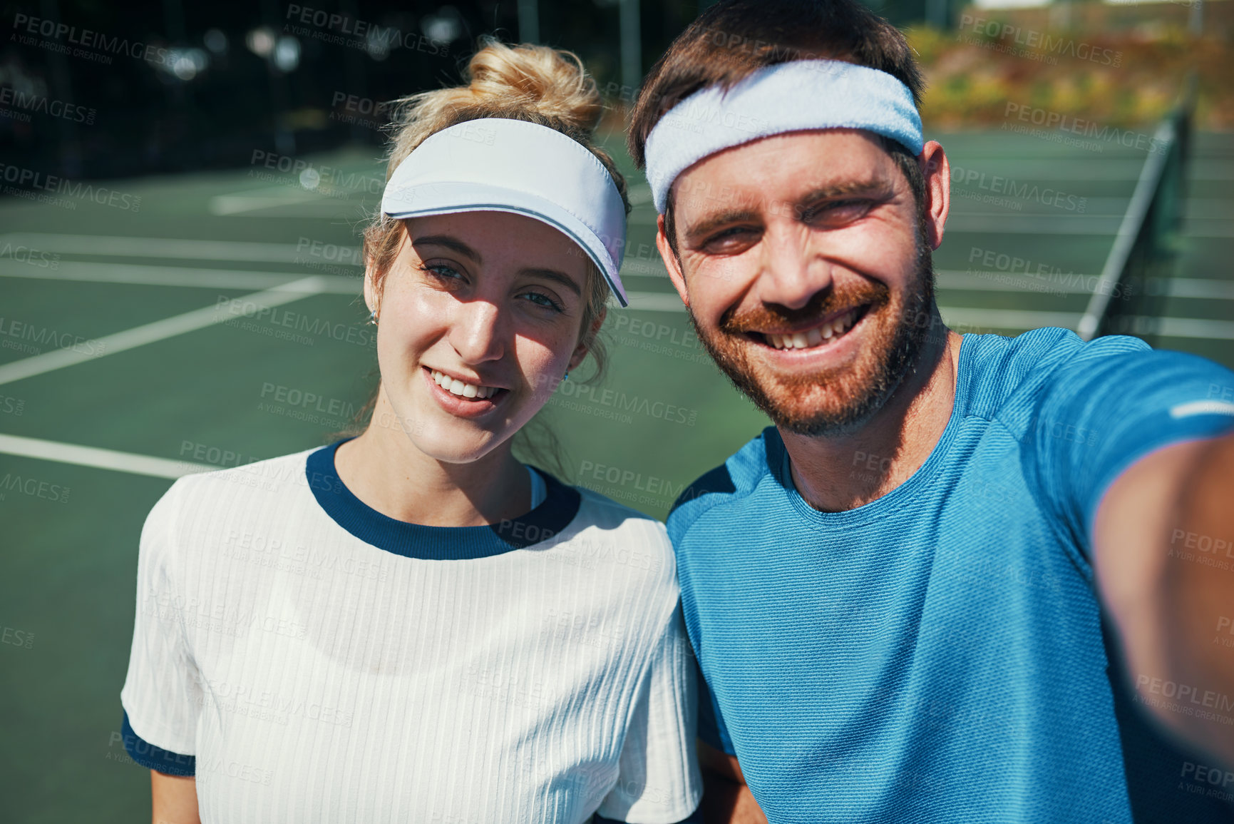 Buy stock photo Portrait of a happy young couple taking selfies while playing tennis together outdoors on the court