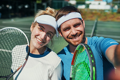 Buy stock photo Portrait of a happy young couple taking selfies while playing tennis together outdoors on the court