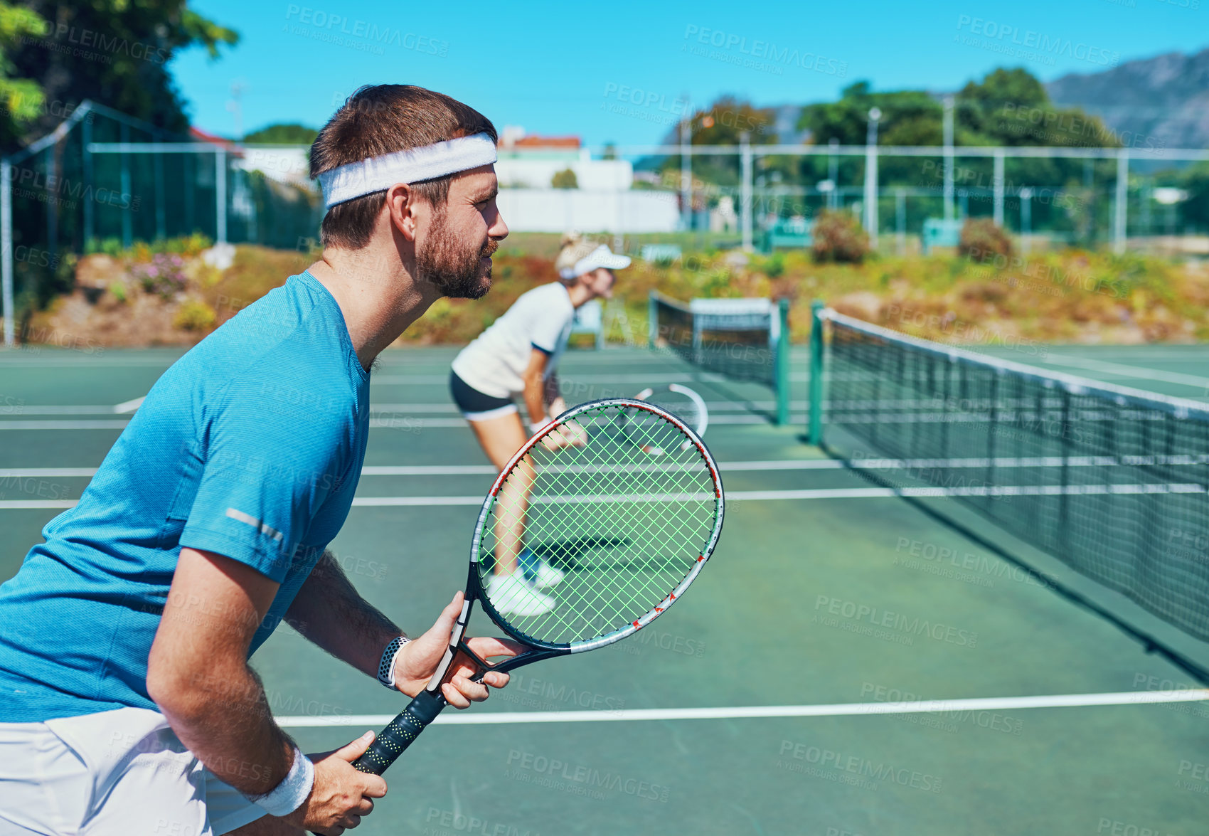 Buy stock photo Cropped shot of a handsome young male tennis player playing together with a female teammate outdoors on a court