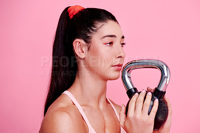 Buy stock photo Studio shot of a sporty young woman exercising with a kettlebell against a pink background