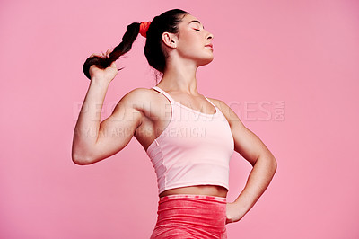 Buy stock photo Studio shot of a sporty young woman holding her ponytail against a pink background