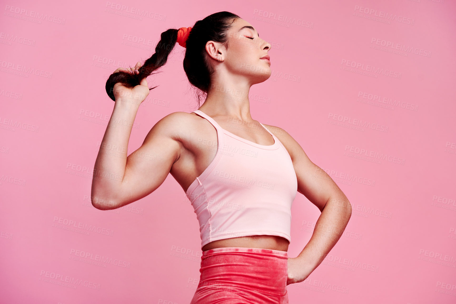 Buy stock photo Studio shot of a sporty young woman holding her ponytail against a pink background