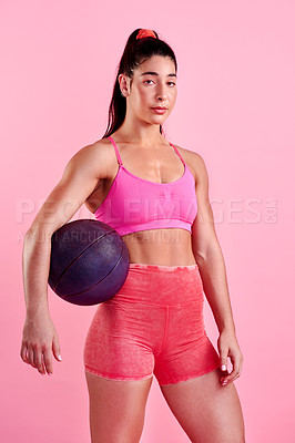 Buy stock photo Studio portrait of a sporty young woman posing with a ball against a pink background