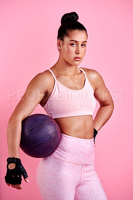 Buy stock photo Studio portrait of a sporty young woman posing with a ball against a pink background
