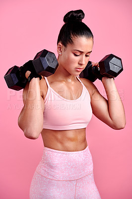 Buy stock photo Studio shot of a sporty young woman exercising with dumbbells against a pink background