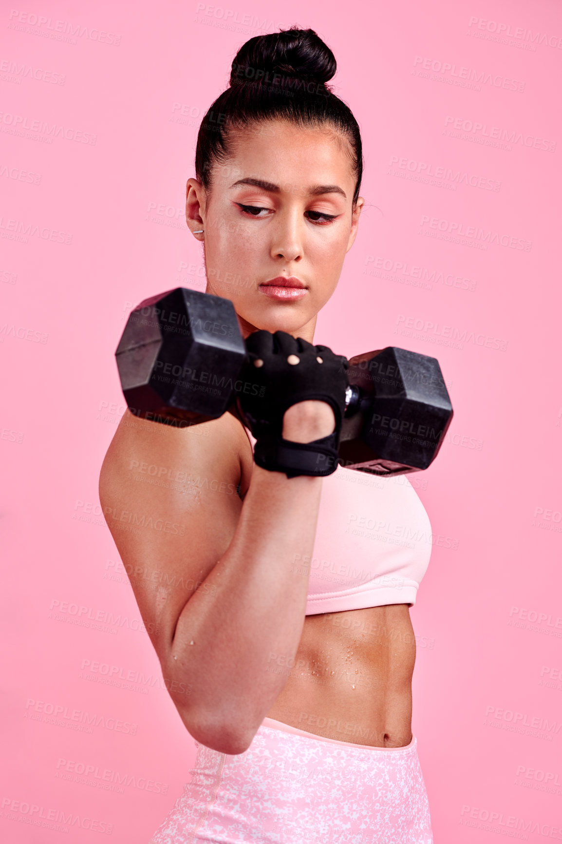 Buy stock photo Studio shot of a sporty young woman exercising with a dumbbell against a pink background
