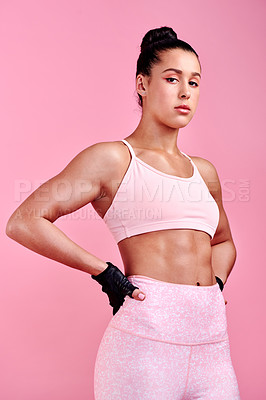 Buy stock photo Studio portrait of a sporty young woman posing with her hands on her hips against a pink background