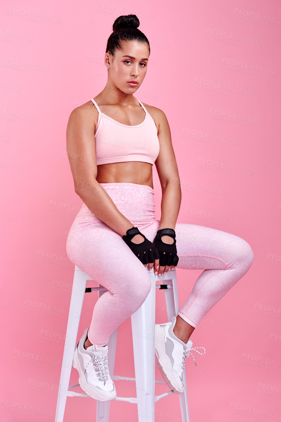 Buy stock photo Studio portrait of a sporty young woman sitting on a chair against a pink background