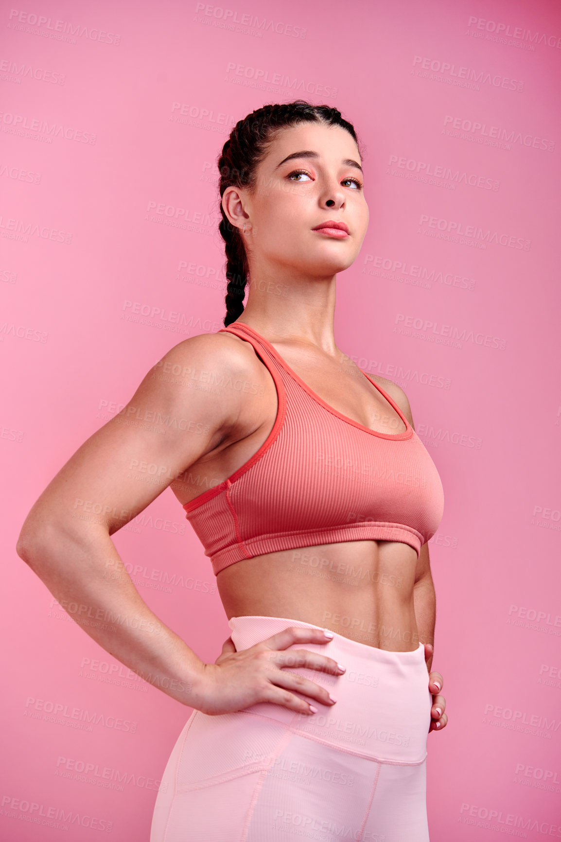 Buy stock photo Studio shot of a sporty young woman posing with her hands on her hips against a pink background