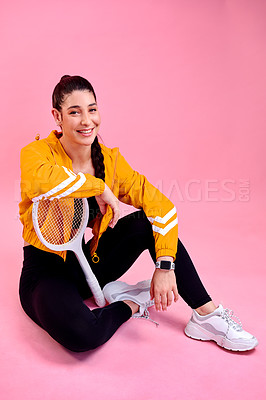 Buy stock photo Studio portrait of a sporty young woman posing with a tennis racket against a pink background