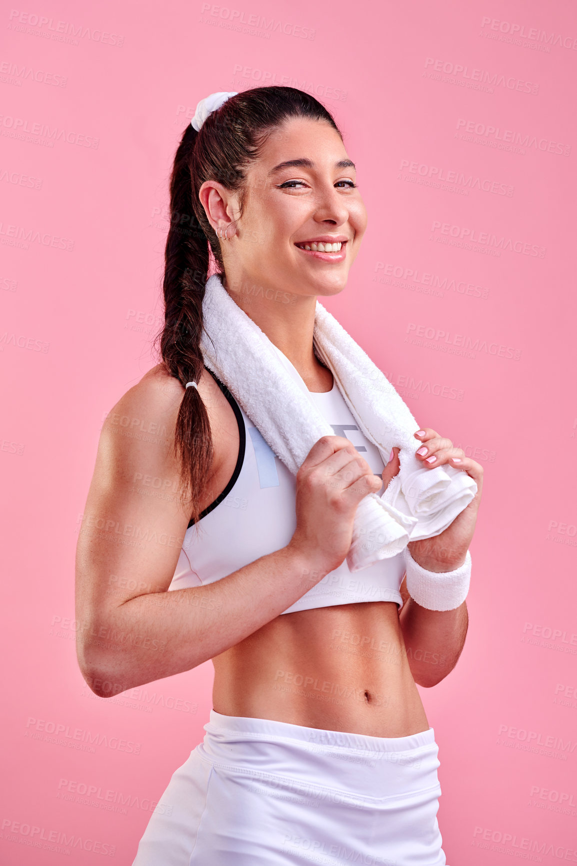 Buy stock photo Studio portrait of a sporty young woman posing with a towel around her neck against a pink background