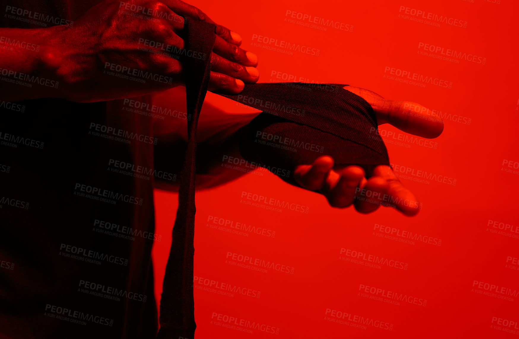 Buy stock photo Read filtered shot of a sporty young man wrapping his hands before boxing