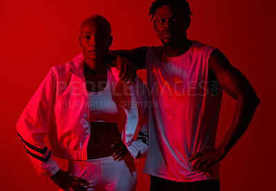 Buy stock photo Red filtered shot of a sporty young man and woman posing together in the studio