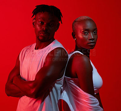 Buy stock photo Red filtered shot of a sporty young man and woman posing together in the studio