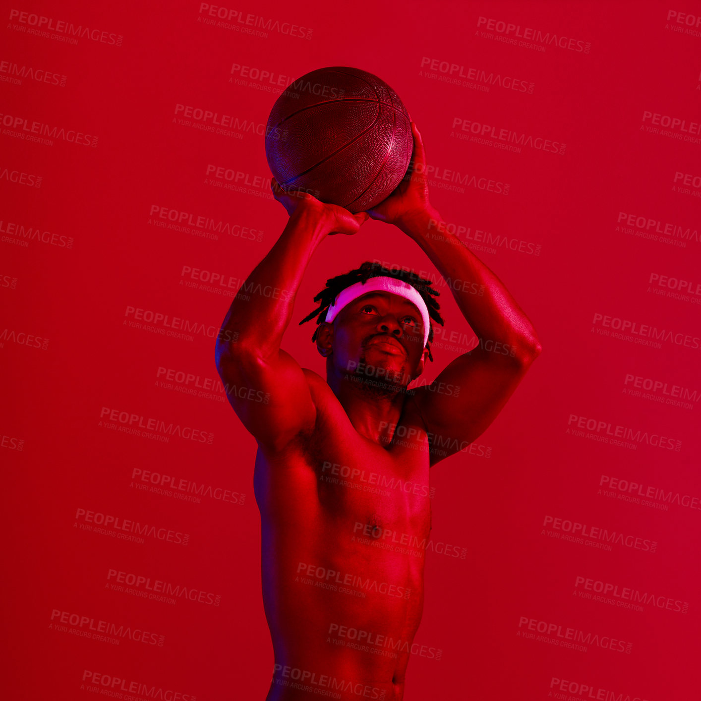 Buy stock photo Red filtered shot of a young sportsman posing with a basketball in the studio