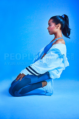 Buy stock photo Full length shot of an attractive young female athlete posing on her knees against a blue background