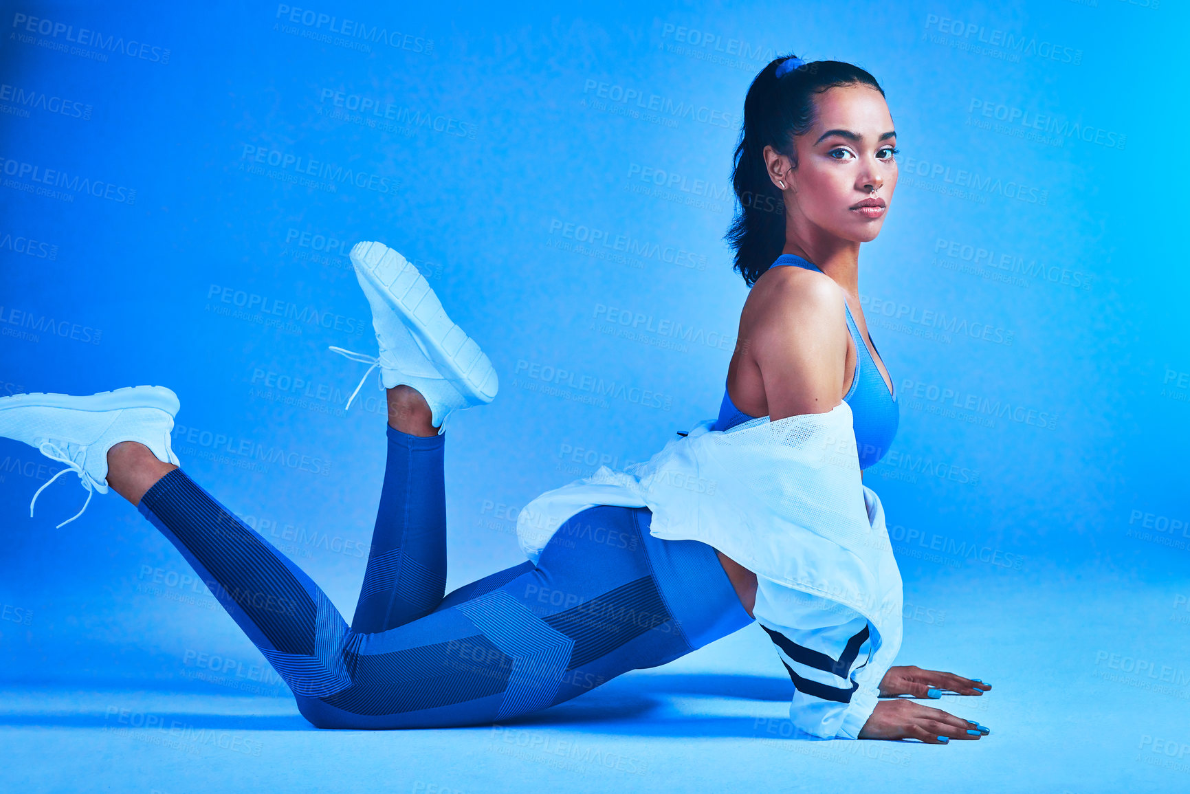 Buy stock photo Full length portrait of an attractive young female athlete posing on the floor against a blue background