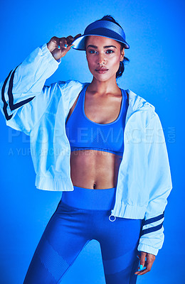 Buy stock photo Cropped portrait of an attractive young female athlete posing against a blue background