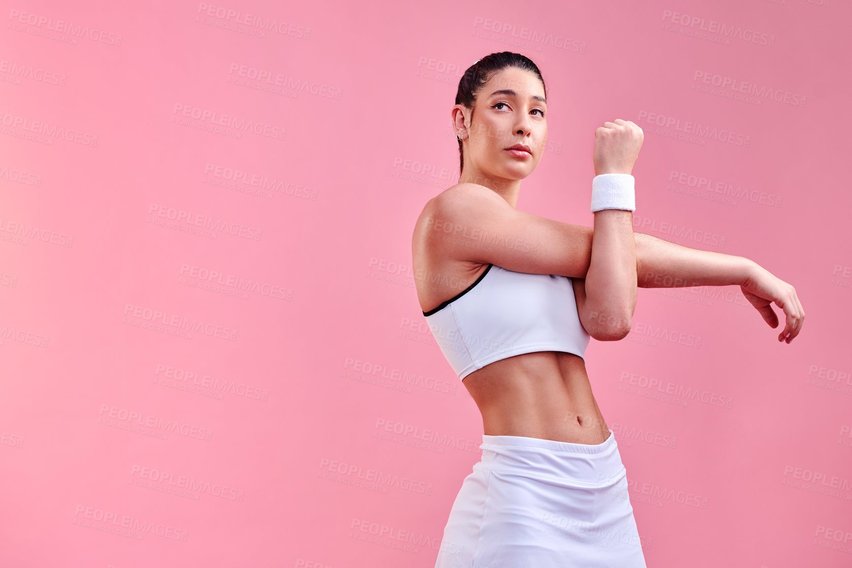 Buy stock photo Studio shot of a sporty young woman stretching her arms against a pink background