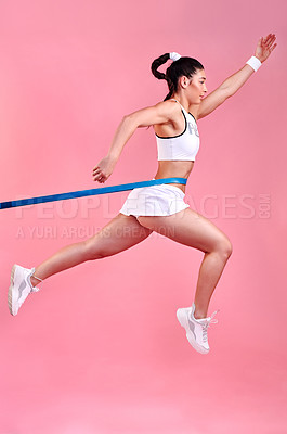 Buy stock photo Studio shot of a sporty young woman jumping with a band around her waist against a pink background