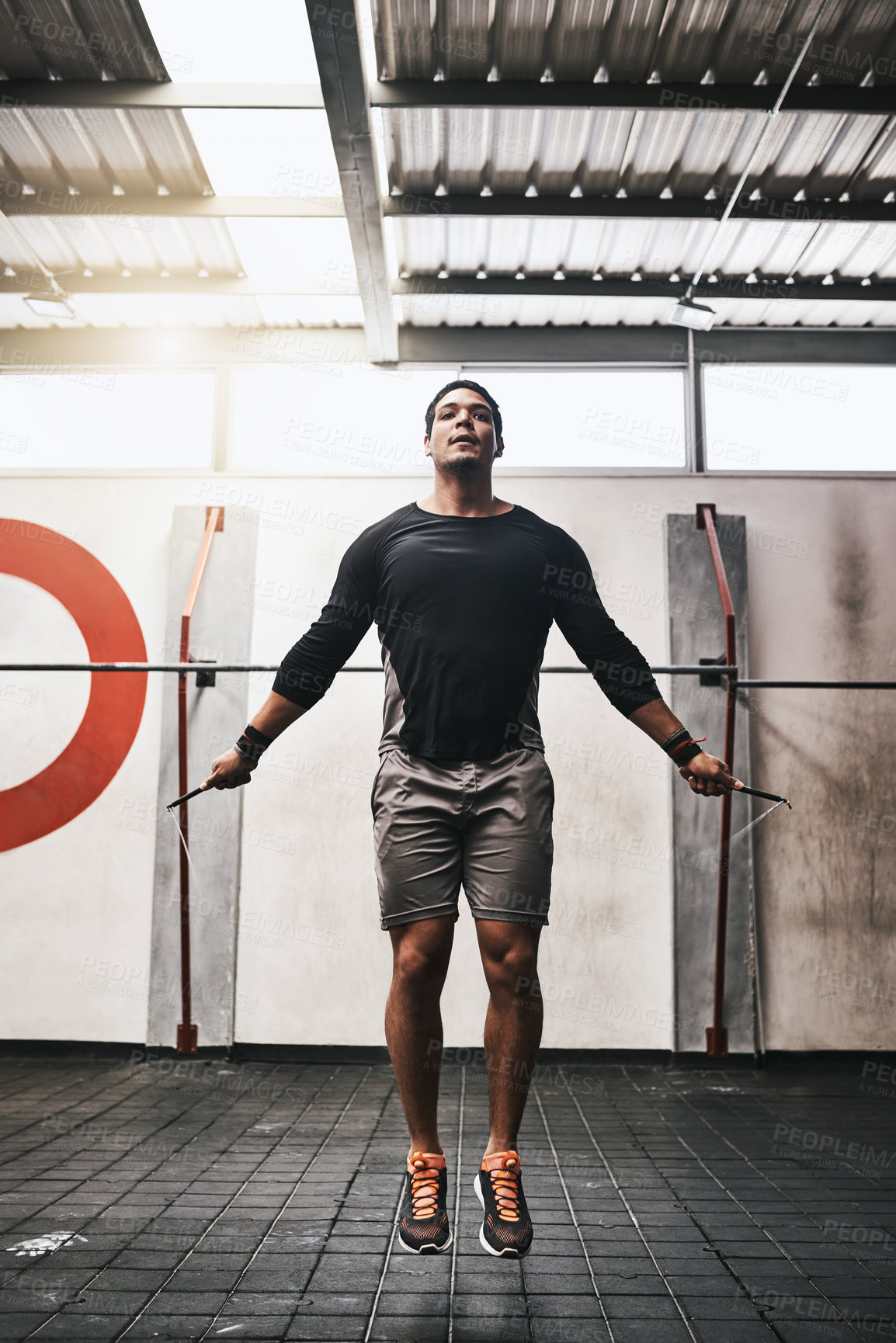 Buy stock photo Shot of a young man skipping rope in a gym