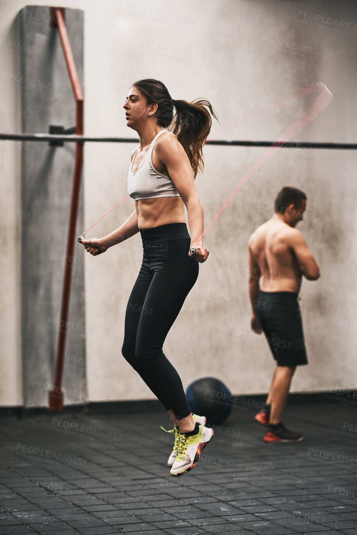 Buy stock photo Shot of a young woman skipping rope in a gym