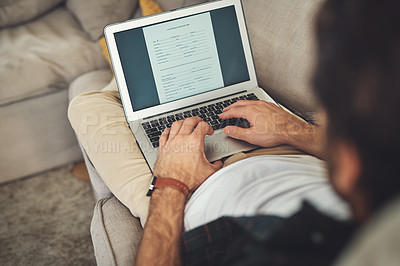 Buy stock photo Shot of an unrecognizable man using his laptop while relaxing on a couch at home