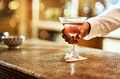 Buy stock photo Cropped shot of an unrecognizable barman serving a drink on the bar counter inside of an establishment at night
