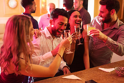Buy stock photo Cropped shot of a group of cheerful young friends having a celebratory toast with their drinks inside of a bar at night