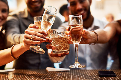 Buy stock photo Cropped shot of a group of unrecognizable friends having a celebratory toast with their drinks inside of a bar at night