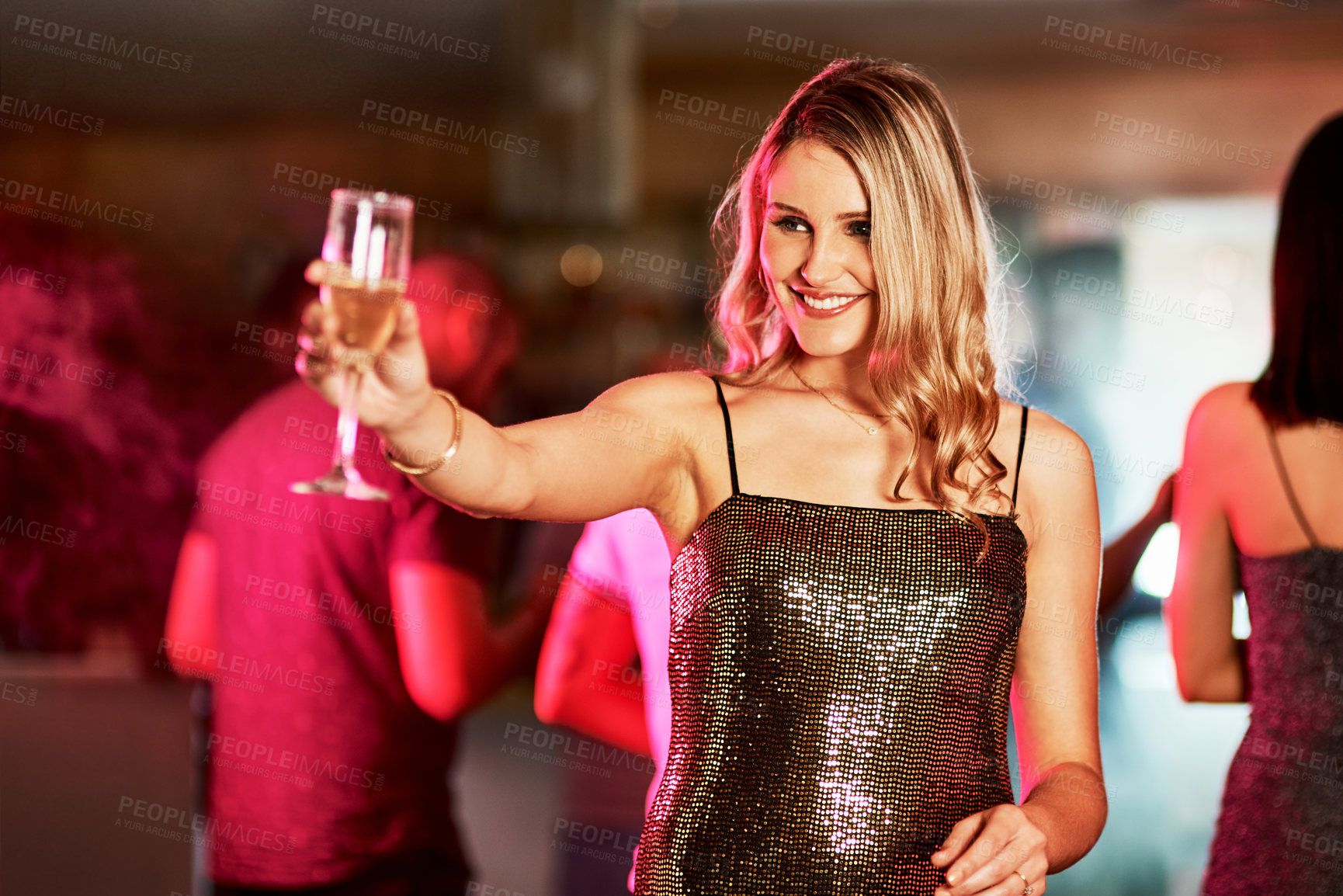 Buy stock photo Cropped shot of an attractive young woman standing in the middle of the dance floor while holding up her drink in celebration inside of a club at night