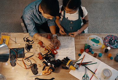 Buy stock photo High angle shot of two adorable young siblings building a robotic toy together at home