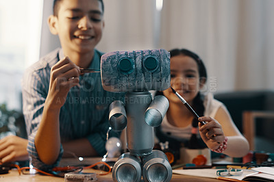 Buy stock photo Shot of two adorable young siblings painting their newly built toy robot at home