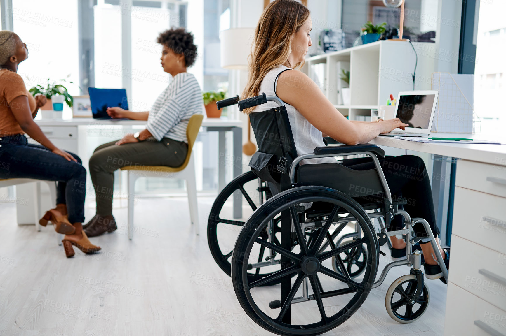 Buy stock photo Shot of a businesswoman sitting in her wheelchair while working at her desk